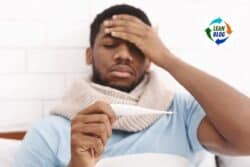 1. Man holding thermometer, appearing sick and tired in a healthcare setting.