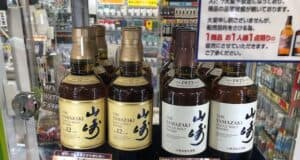 A display of Yamazaki Whisky bottles in a Japanese store, featuring Yamazaki 12 Year Old Single Malt and Yamazaki 1923 Single Malt bottles with price tags in Japanese yen.