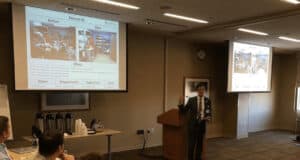 1. Presenter giving lean improvement case study to hospital staff in conference room.
