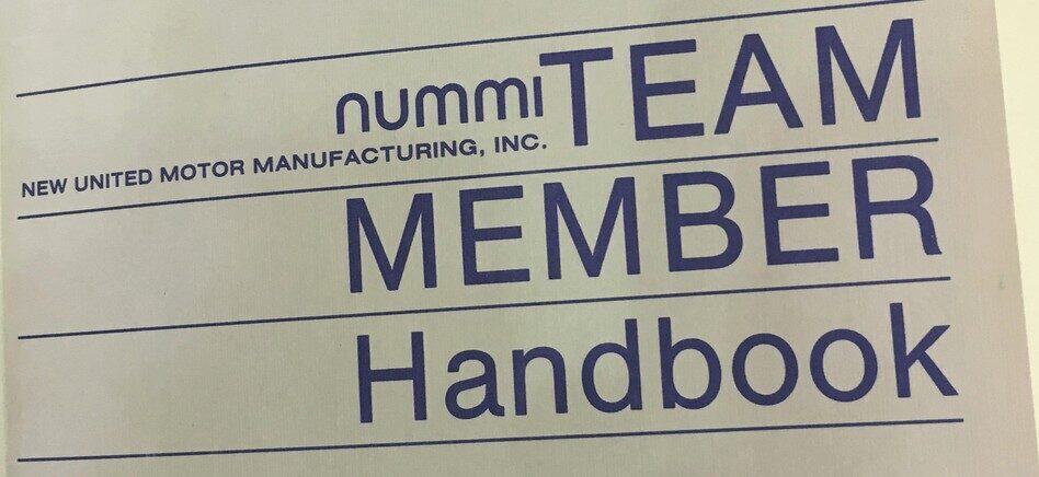 Team member handbook cover for Nummi, a Toyota manufacturing plant, emphasizing team collaboration and organizational standards.