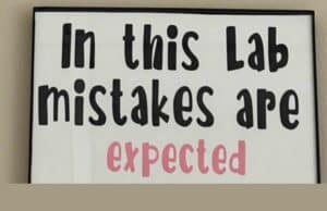 If Mistakes Are Expected, We Can React Appropriately and Constructively (and Even Prevent Them) A sign with bold text that reads "In this Lab mistakes are expected," emphasizing a culture that embraces learning from errors.