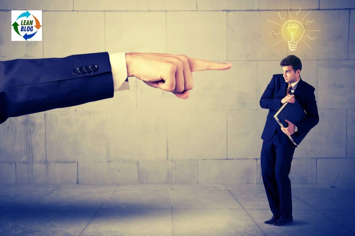 arm and finger of a workplace boss pointing a finger of blame at an employee who looks scared to share their idea.