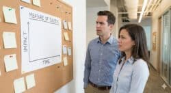 Blank chart showing metrics for success, impact over time. Two concerned employees review blank chart, lacking metrics.