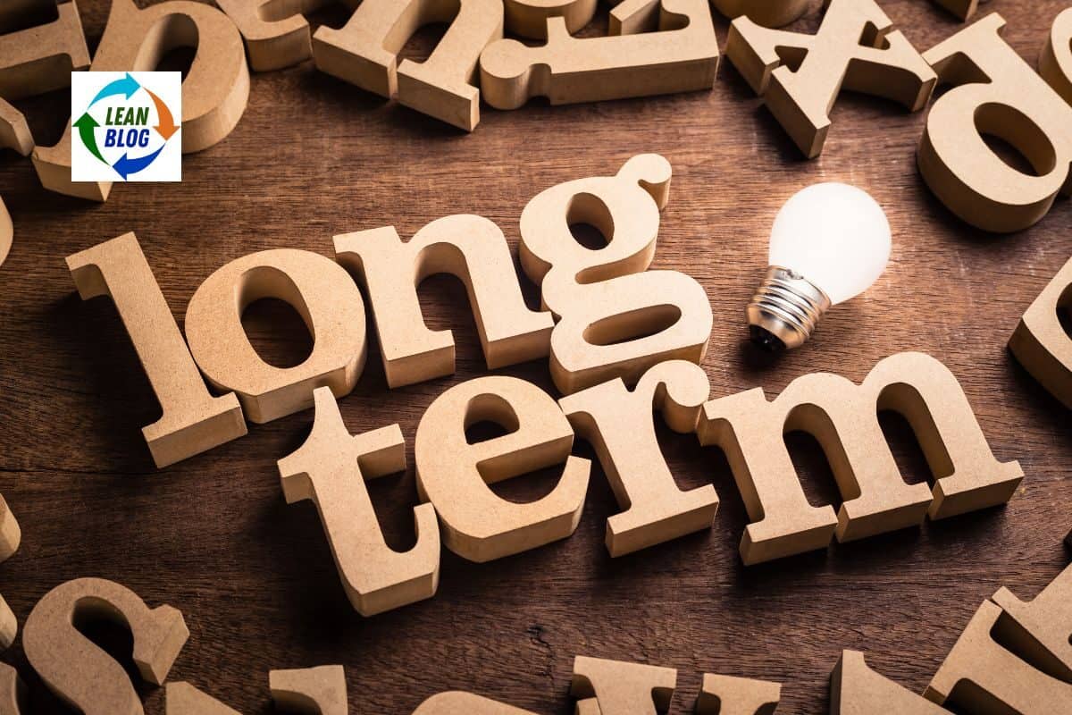 "Long term" spelled out with wooden letter blocks, with a light bulb, on a wooden surface.
