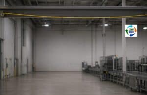 New Book Announcement: Psychological Safety for Lean Leaders — Vote on the Title A yellow andon cord stretches horizontally across the upper part of an empty factory interior, slightly slack and attached to a dark overhead beam. Below it, a large expanse of smooth concrete floor and muted gray walls creates generous open space, while a softly blurred production line runs along the right side. Natural overhead light and subdued editorial color grading give the scene a calm, documentary feel.