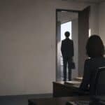 A person stands in an office doorway facing a seated leader, the moment a problem gets delivered