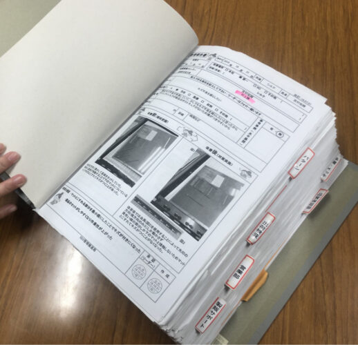 Kaizen report for an anti-scratch fixture, filed in a tabbed binder of improvement sheets by department
