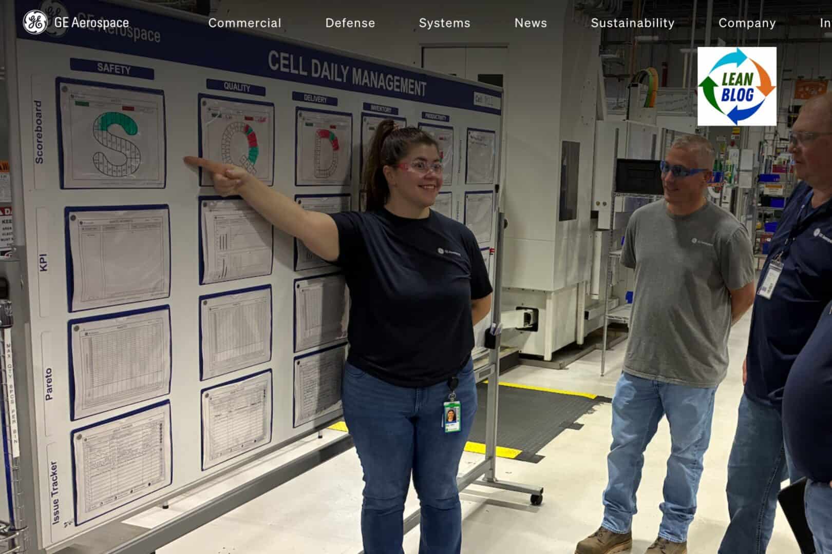 GE Aerospace employees review a cell daily management board displaying safety, quality, delivery, inventory, and productivity measures on the factory floor.