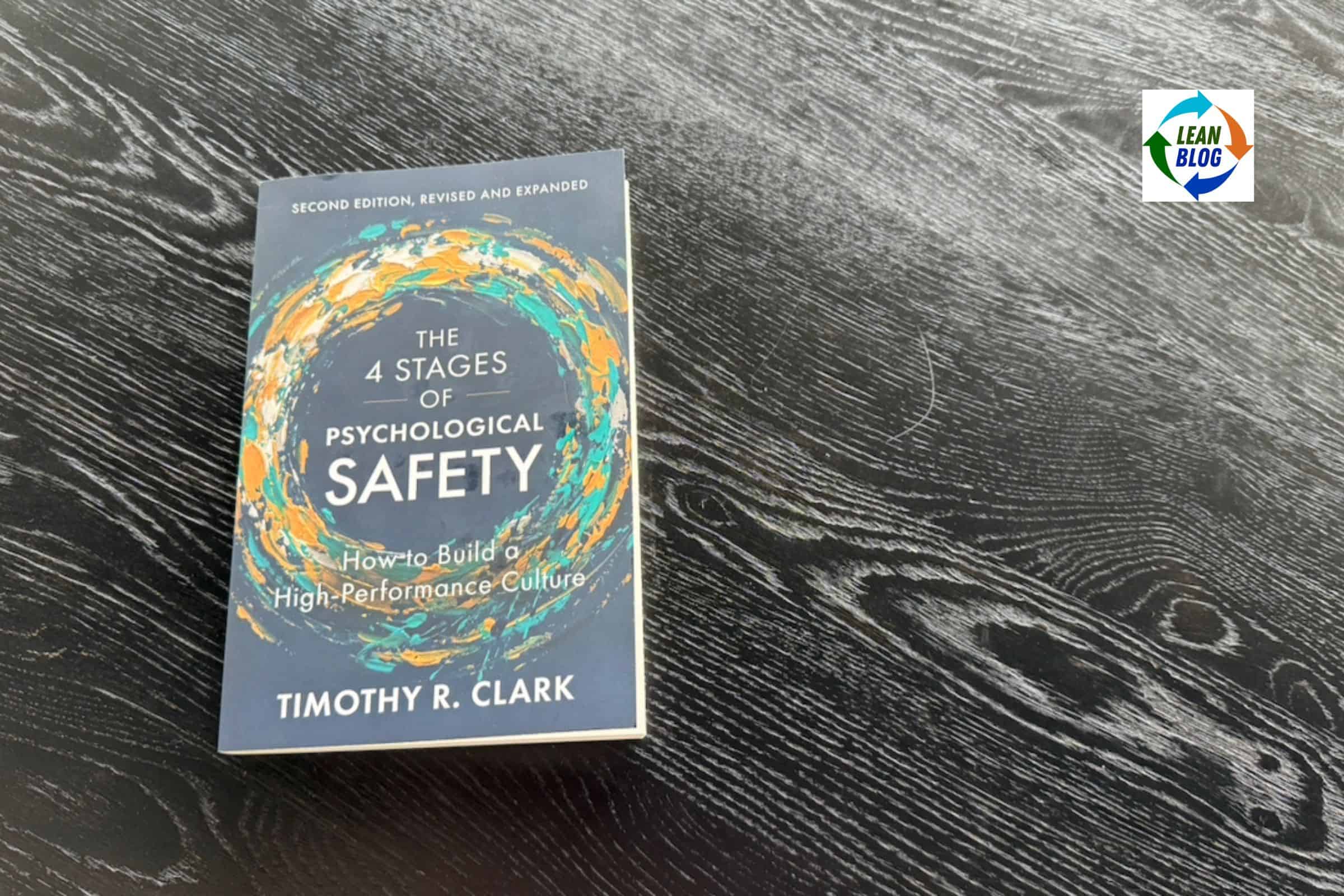 Book cover titled The 4 Stages of Psychological Safety by Timothy R. Clark, resting on a dark wood table.