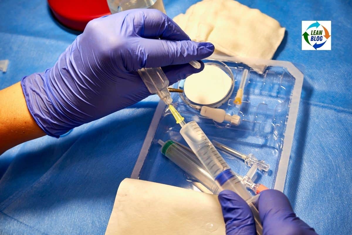 Hands in blue medical gloves preparing a syringe over a sterile plastic tray with needles and medical supplies