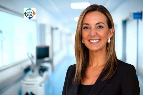 emily swaney in a black blazer smiling in a bright hospital corridor with blurred medical equipment and a Lean Blog logo
